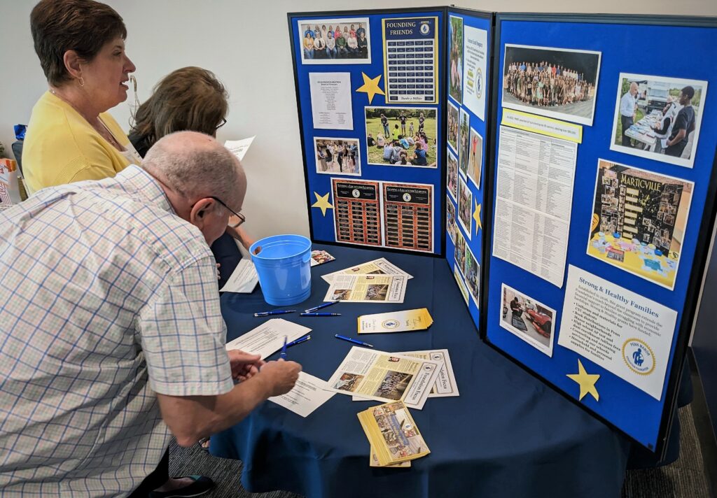 Three retirees look at a display board filled with photos and information.