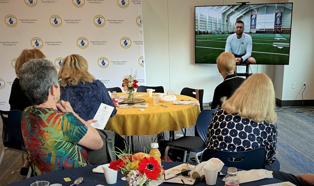 Several people watch a livestream presentation by Mike Trier